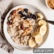 Overhead image of a bowl of oatmeal topped with peanut butter, banana and berries.