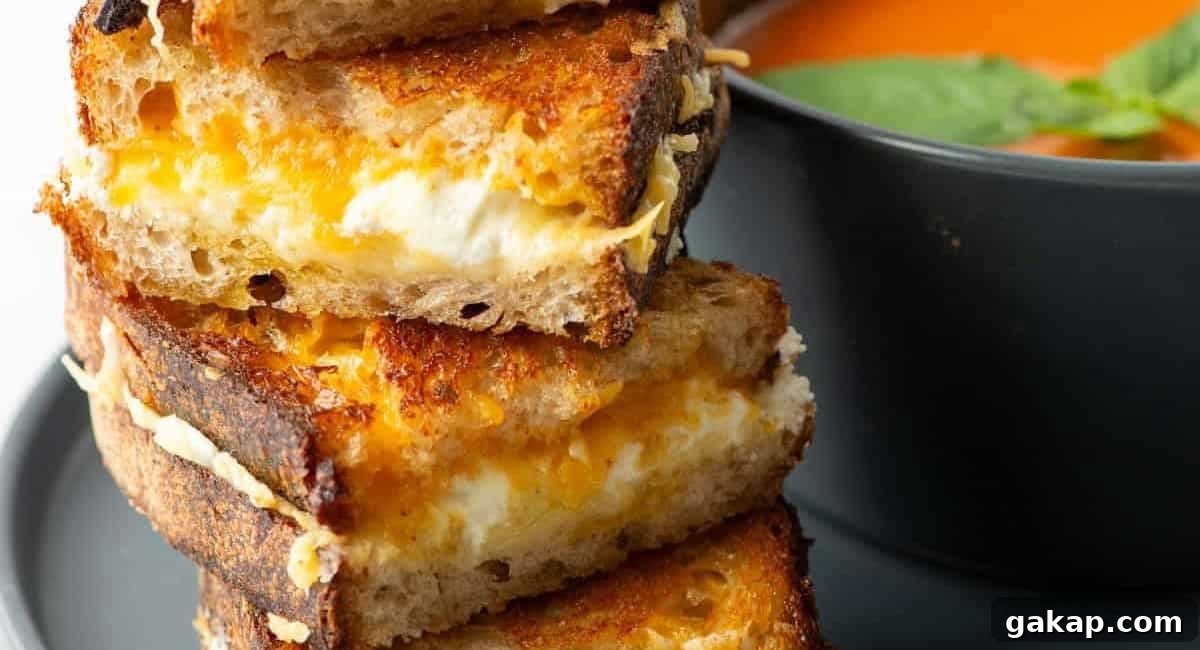 Side profile image of four cheese grilled cheese with bowl of tomato soup next to it. 