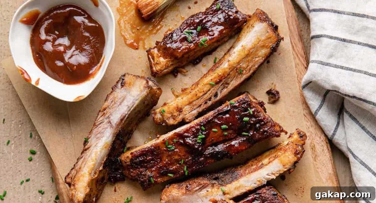 Overhead image of bbq St. Louis ribs on wooden board with bbq sauce on the side. 