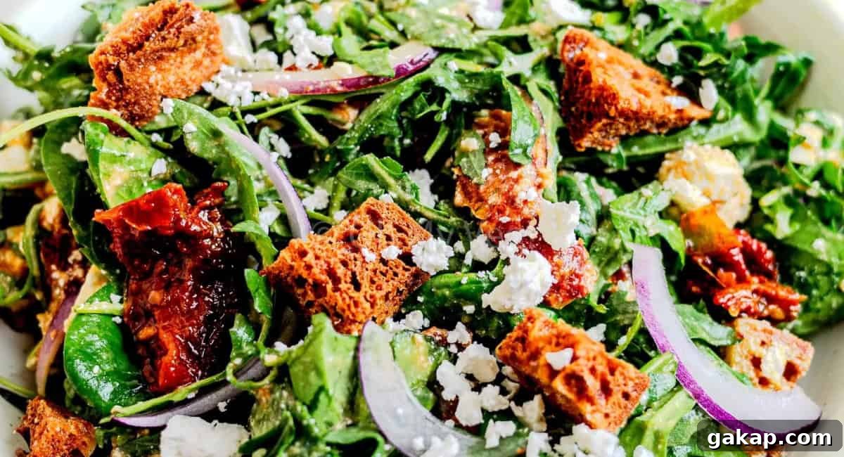 Overhead image of spinach and arugula salad with garnish. 