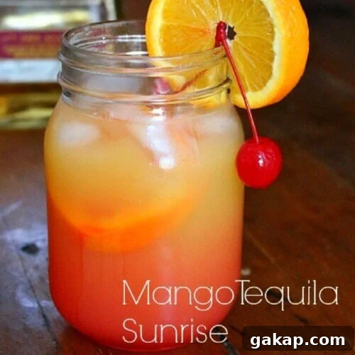 Closeup of a mango tequila sunrise garnished with an orange and a cherry.