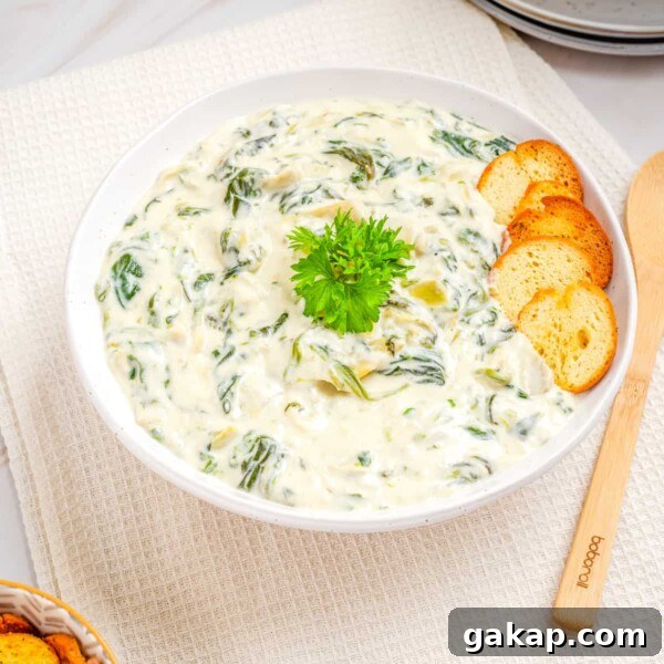 Overhead view of the spinach artichoke dip in a white bowl.