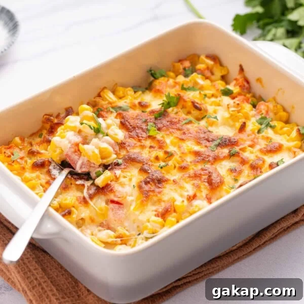 An image of cream cheese corn dip in a baking dish with a spoon full of the dip rests on top.