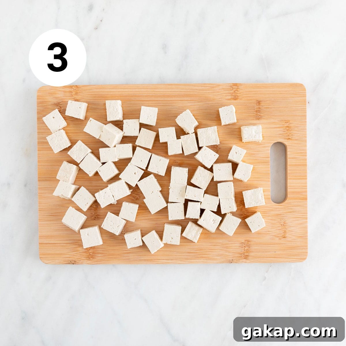Tofu cubes on wooden cutting board.