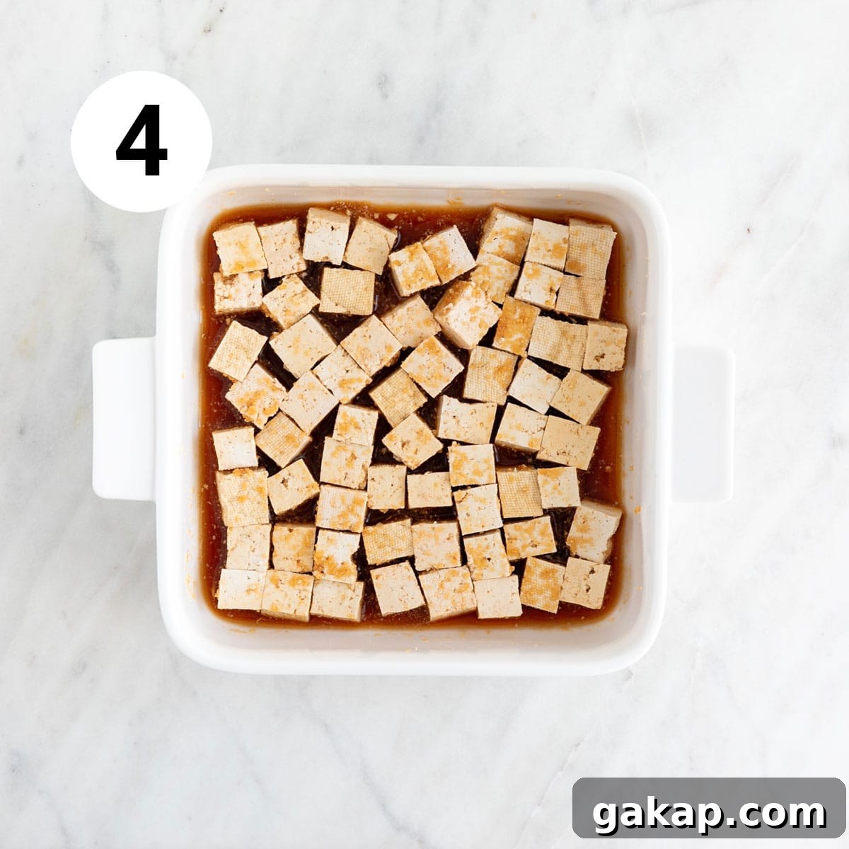 Tofu cubes marinating in a baking dish.