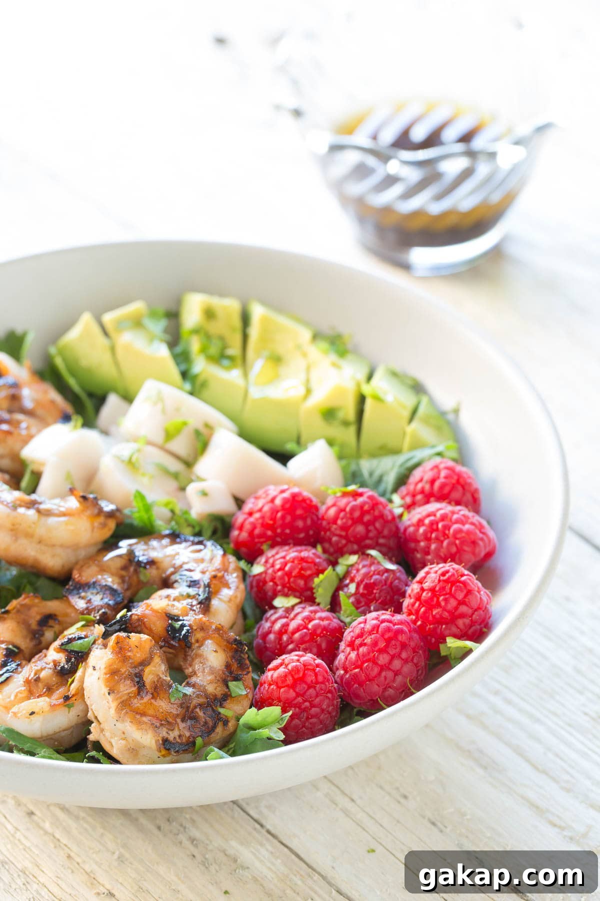 Grilled shrimp, heart of palm, raspberries, and avocado in a bowl for a salad.