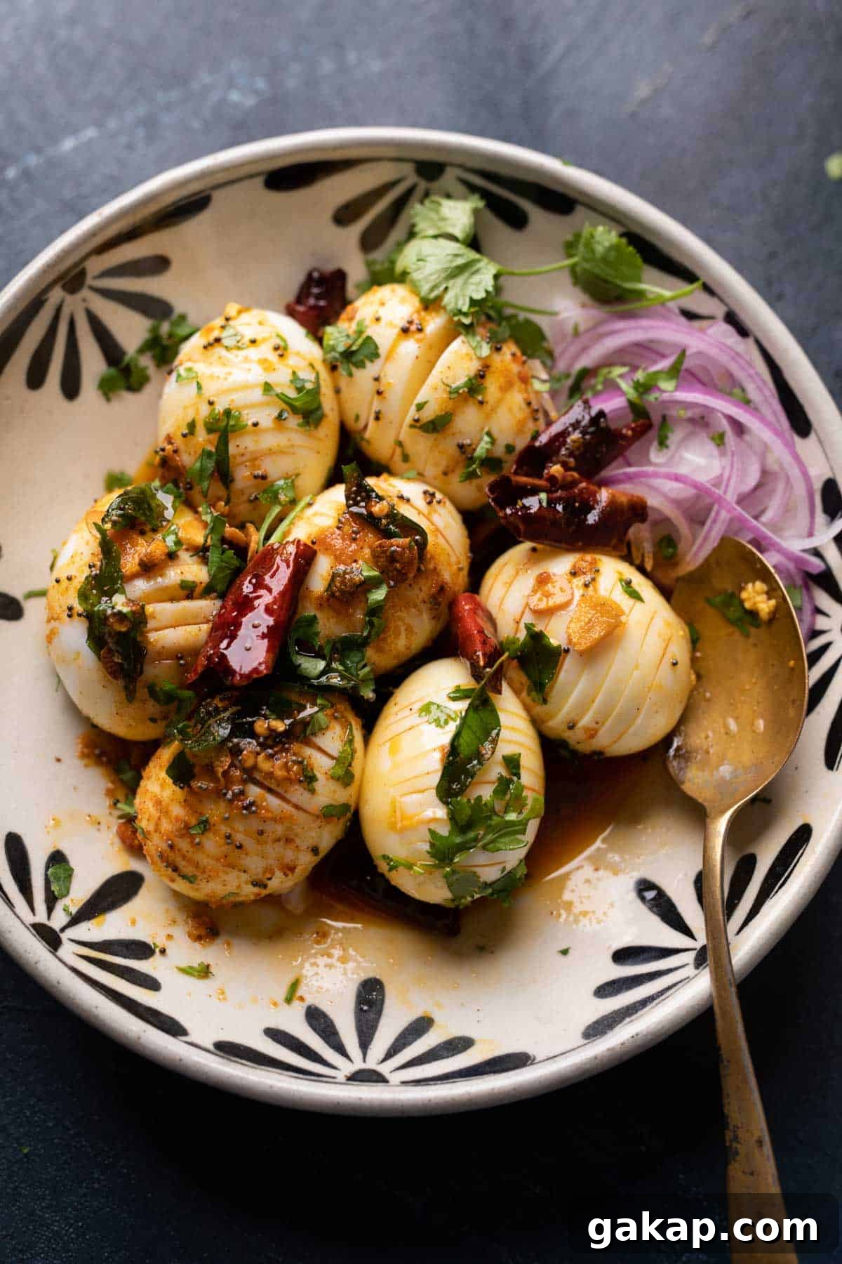 Egg tadka served in a black and white bowl with sliced onions on the side