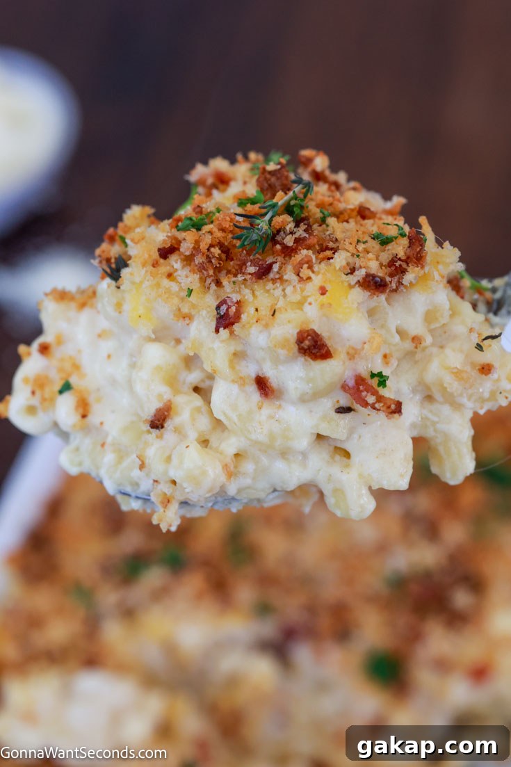 Smoked gouda mac and cheese has tender al dente pasta in a super creamy, velvety cheese sauce, topped with a buttery, crunchy crumb topping. It's so gouda! #macandcheese #macaroniandcheese Scooping smoked gouda mac and cheese with bacon