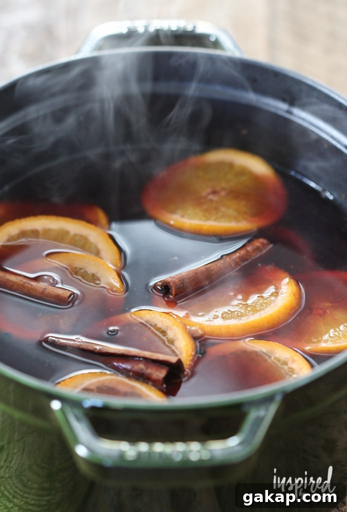 14 Memorable Friendsgiving Recipes Everyone Will Rave About 12 mulled wine in a pot with orange slices and cinnamon sticks.