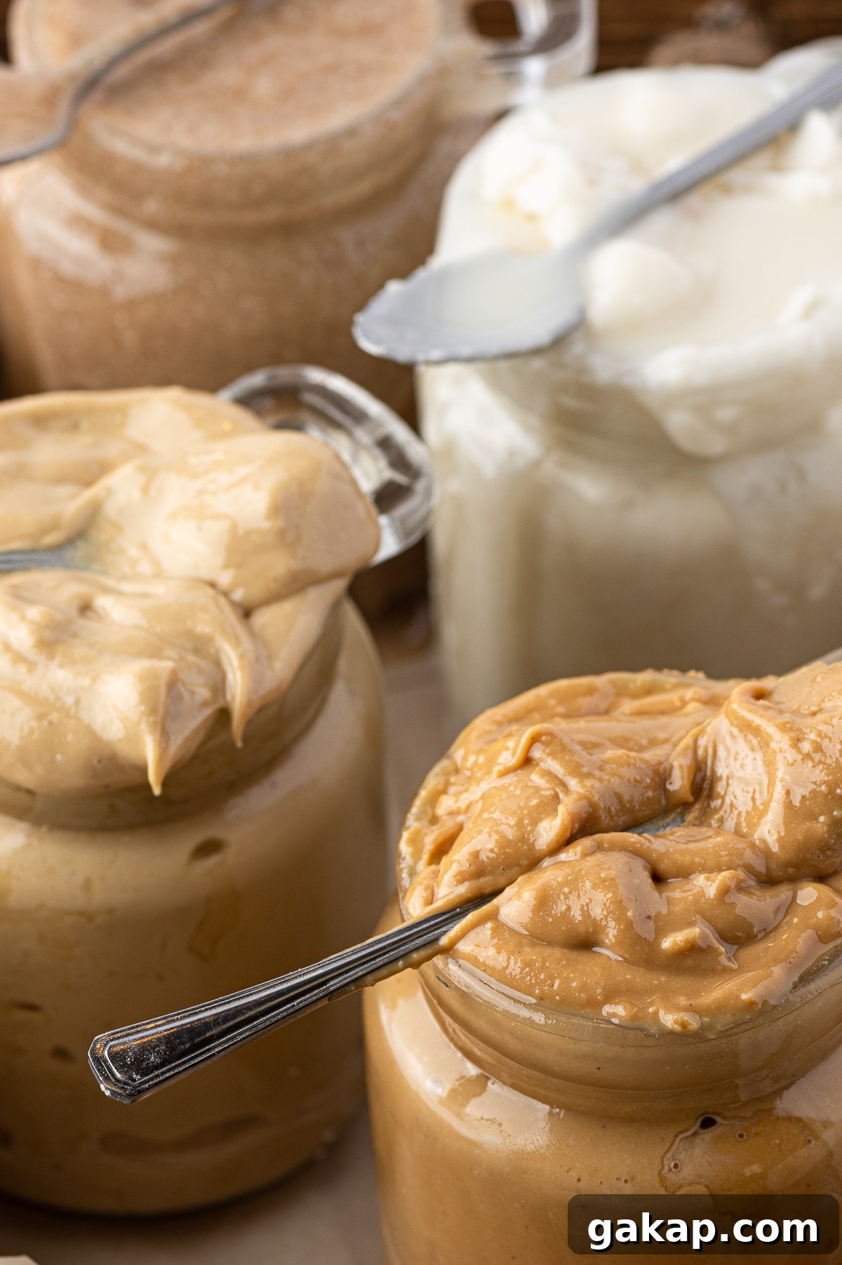 Top Nut Butters for Low-Carb Baking: Almond, Peanut & More 8 Jars of nut butters with small spoons laying across the top jar opening