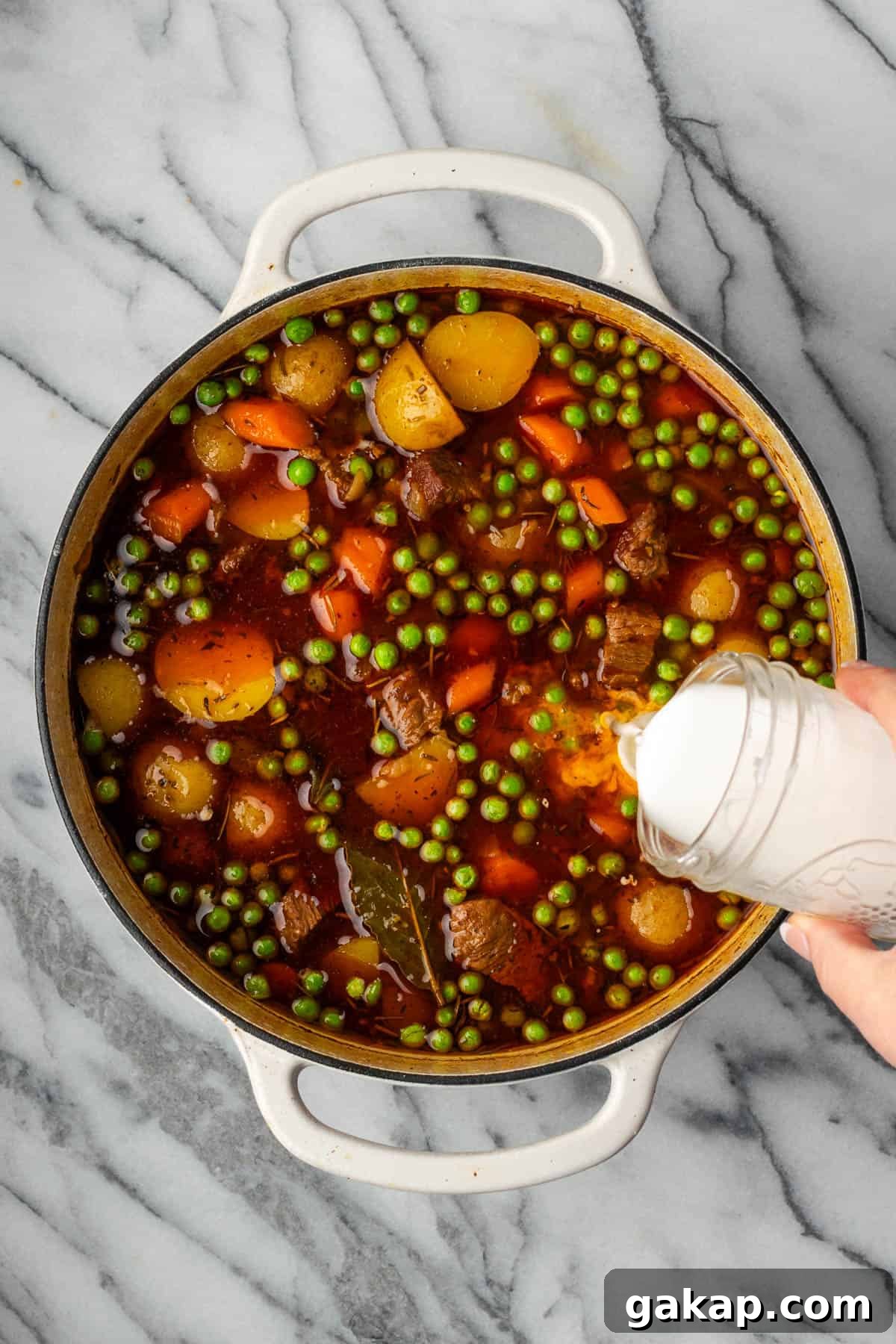 A starch slurry being stirred into the finished pot of beef stew.