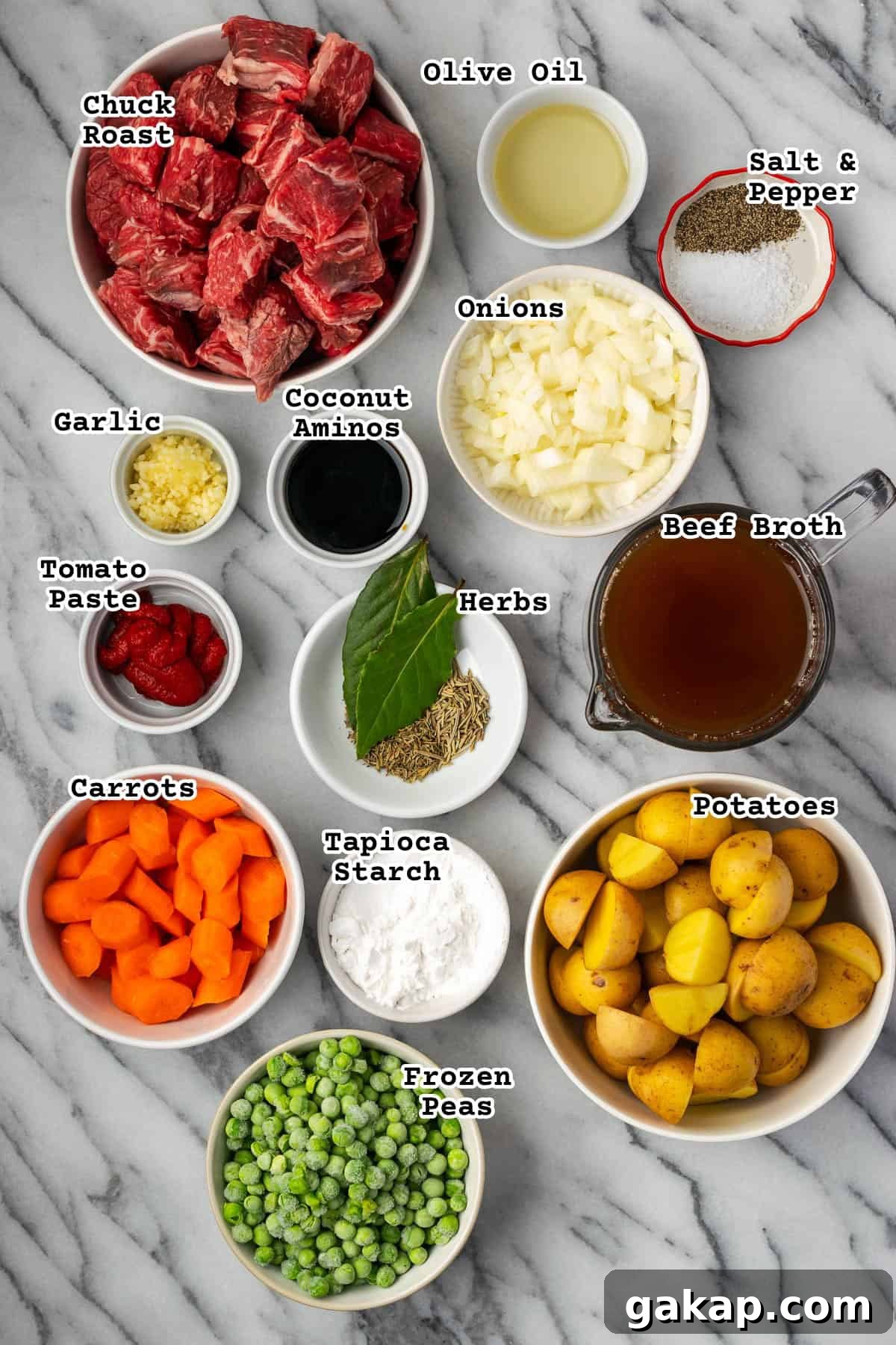 Ingredients for beef stew sitting on a marble counter. 
