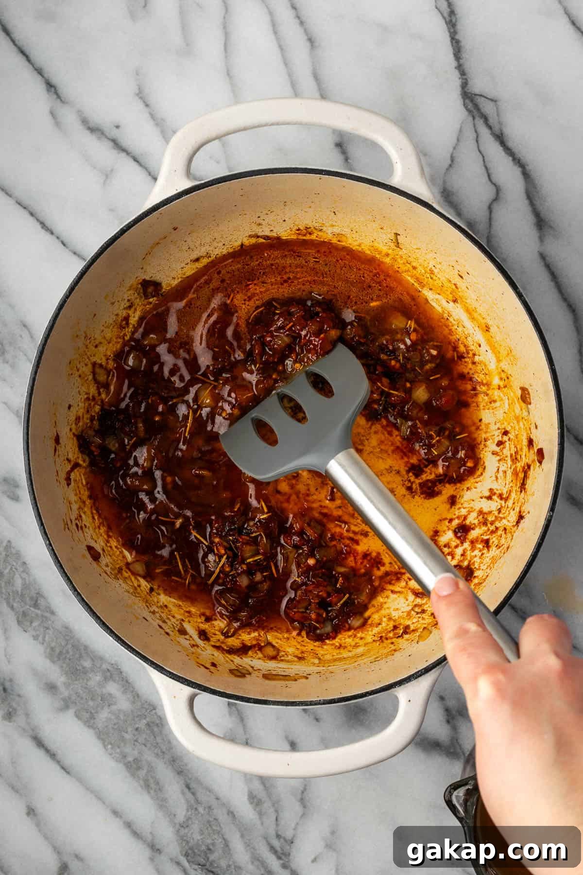 A spatula scraping the food from the bottom of the pot.