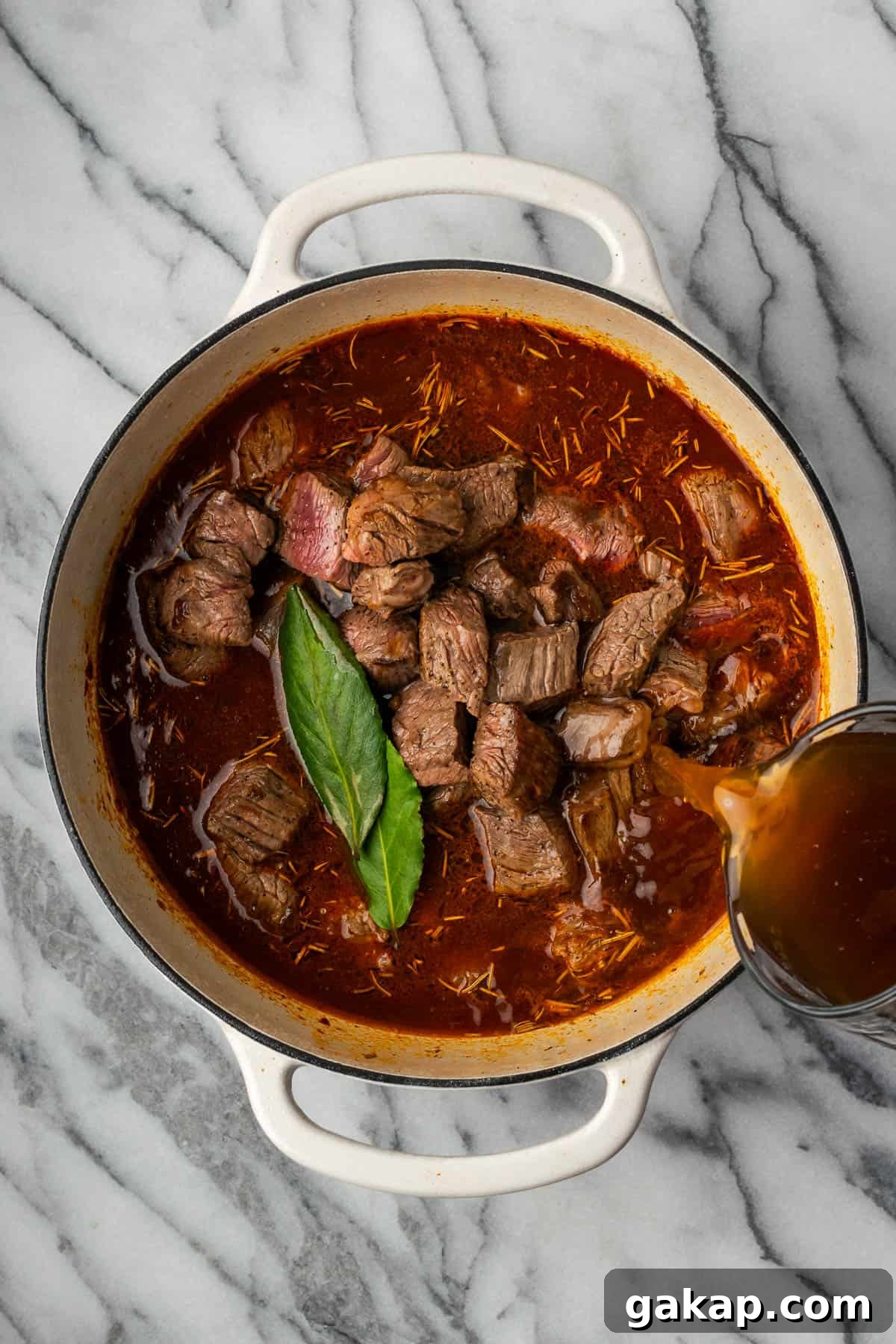 Cooked beef, beef broth and bay leaves are added to the pot. 