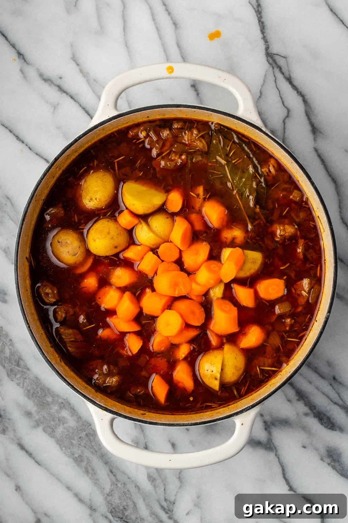 Carrots and potatoes added to the pot with the cooked beef.