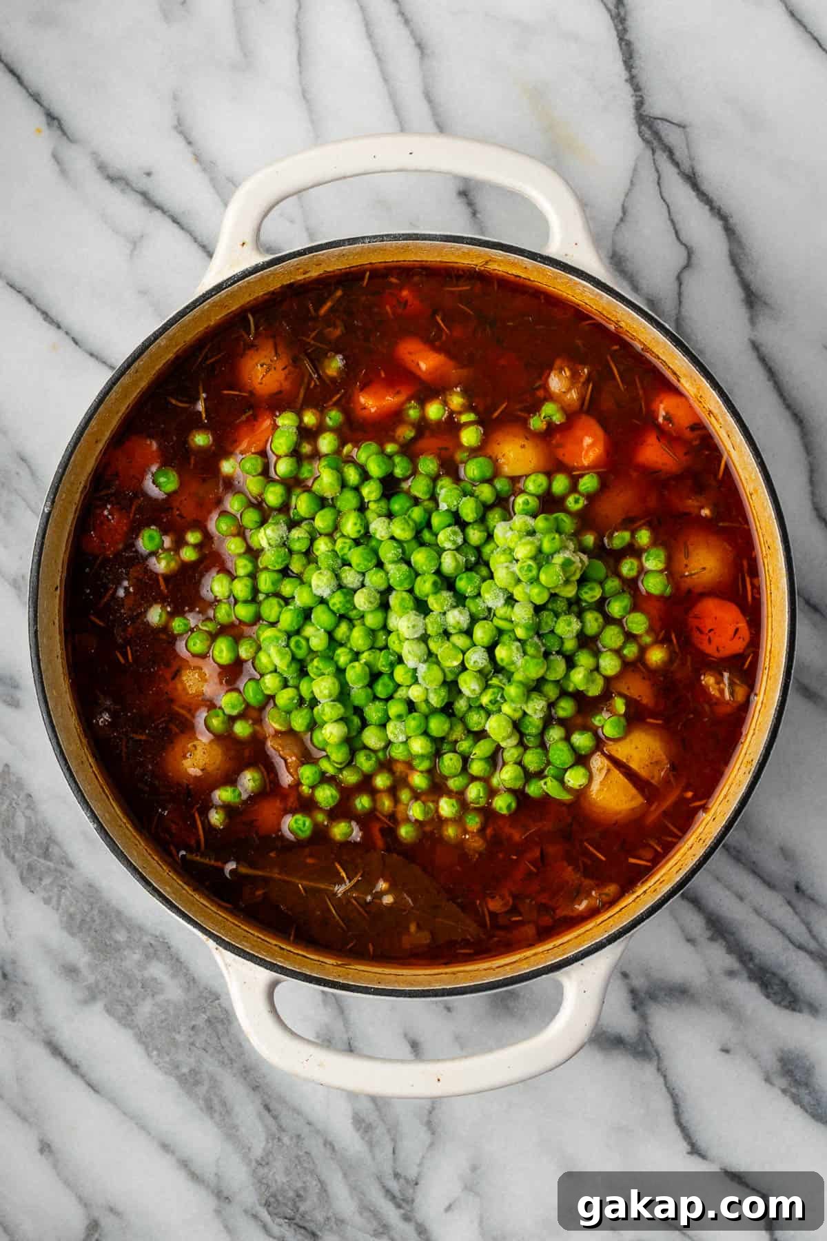 Frozen peas being added into the cooked beef stew.