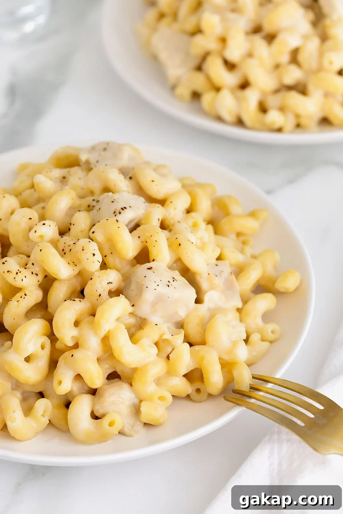 A large white dinner plate filled with cavatappi pasta in a white sauce with chicken.
