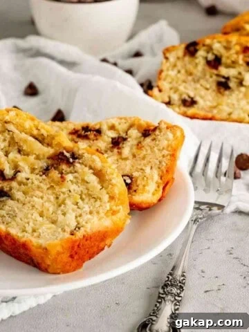 Two slices of chocolate chip banana bread on a white plate with cut slices in the background.