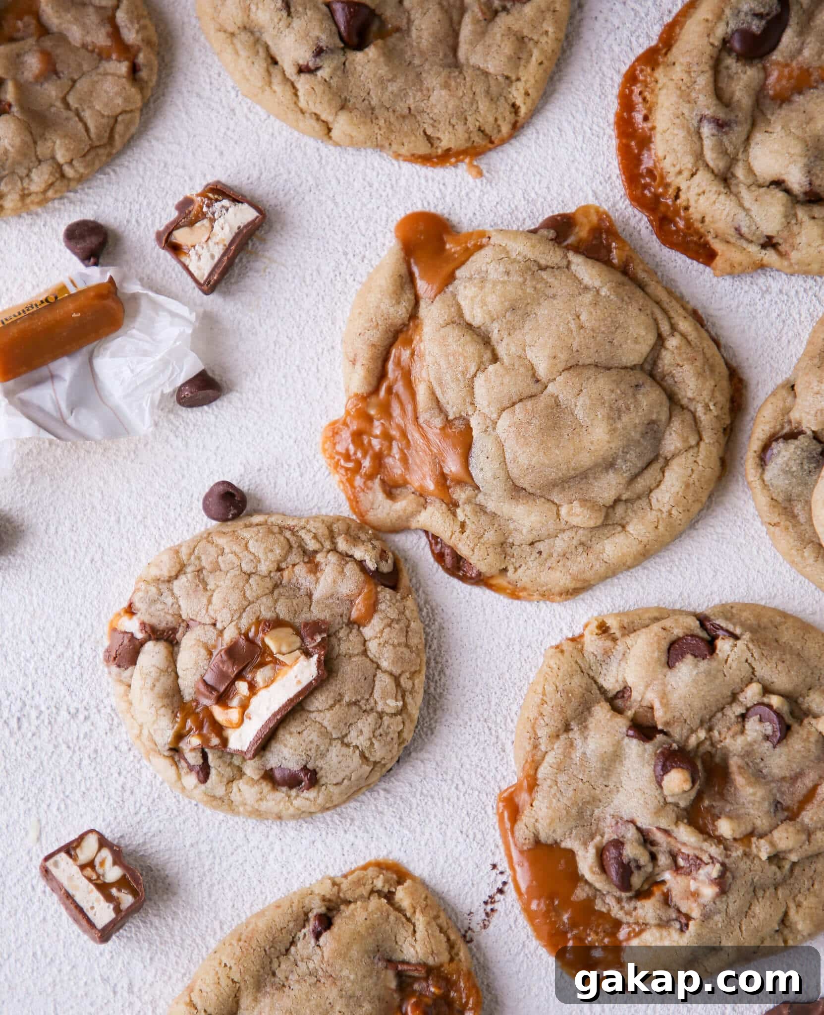 Brown Butter Snickers Caramel-Stuffed Chocolate Chip Cookies 2 Caramel Stuffed Brown Butter Snickers Chocolate Chip Cookies arranged on white surface