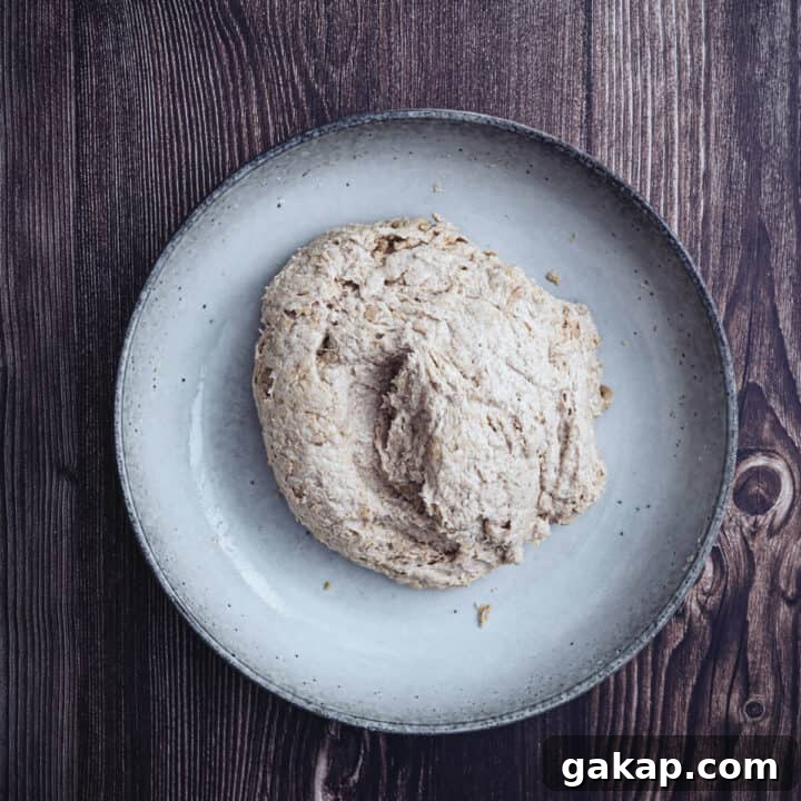 buckwheat pita dough mixed in a large ceramic bowl on a wooden surface.