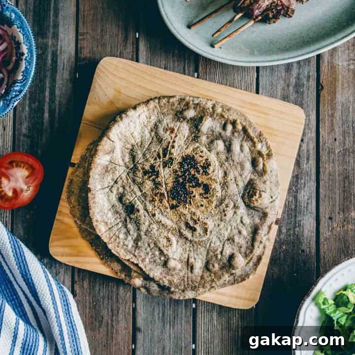 cooked buckwheat pita bread served on a wooden board with Greek souvlaki and condiments.
