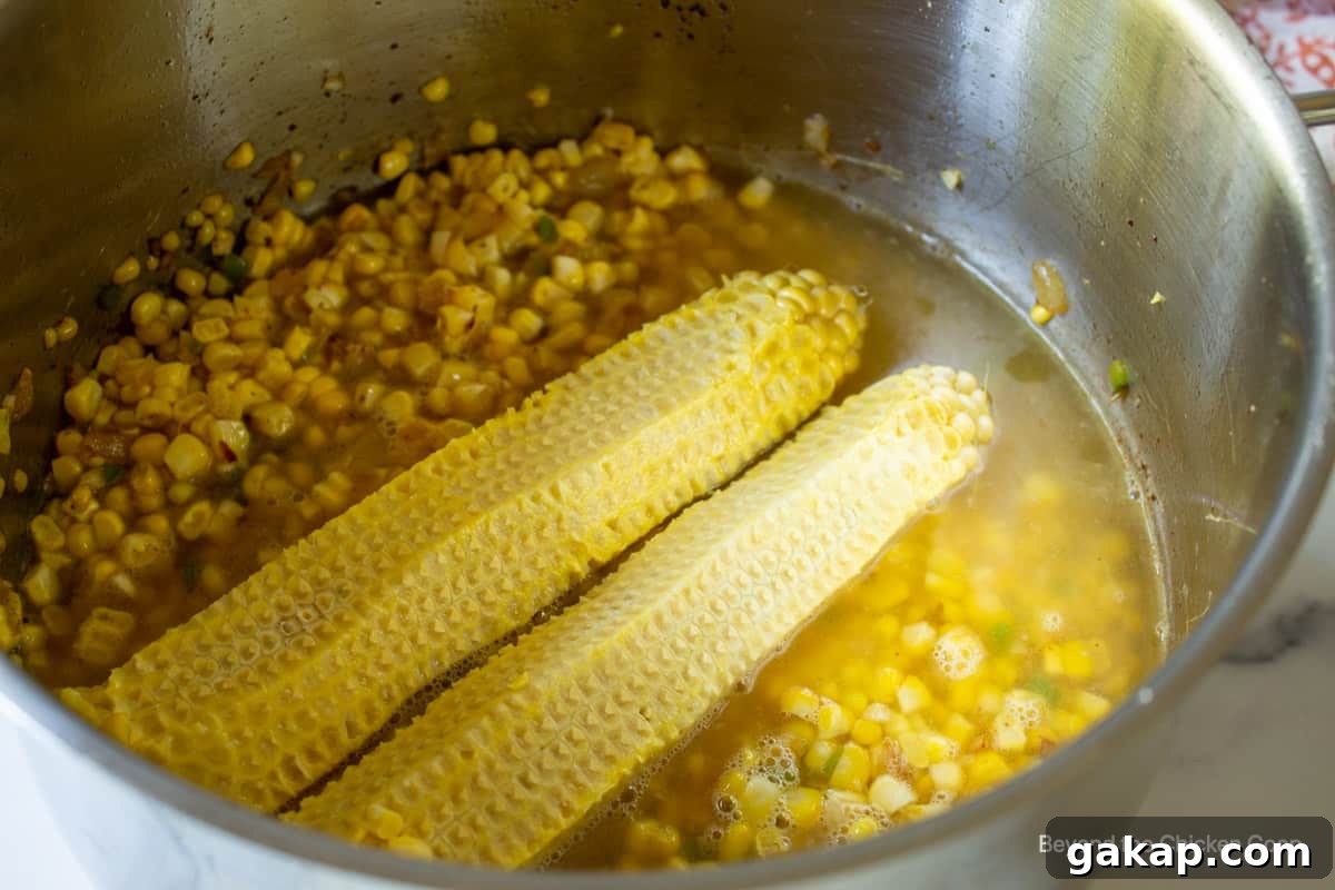 Corn cobs in a pot filled with corn and chicken stock.