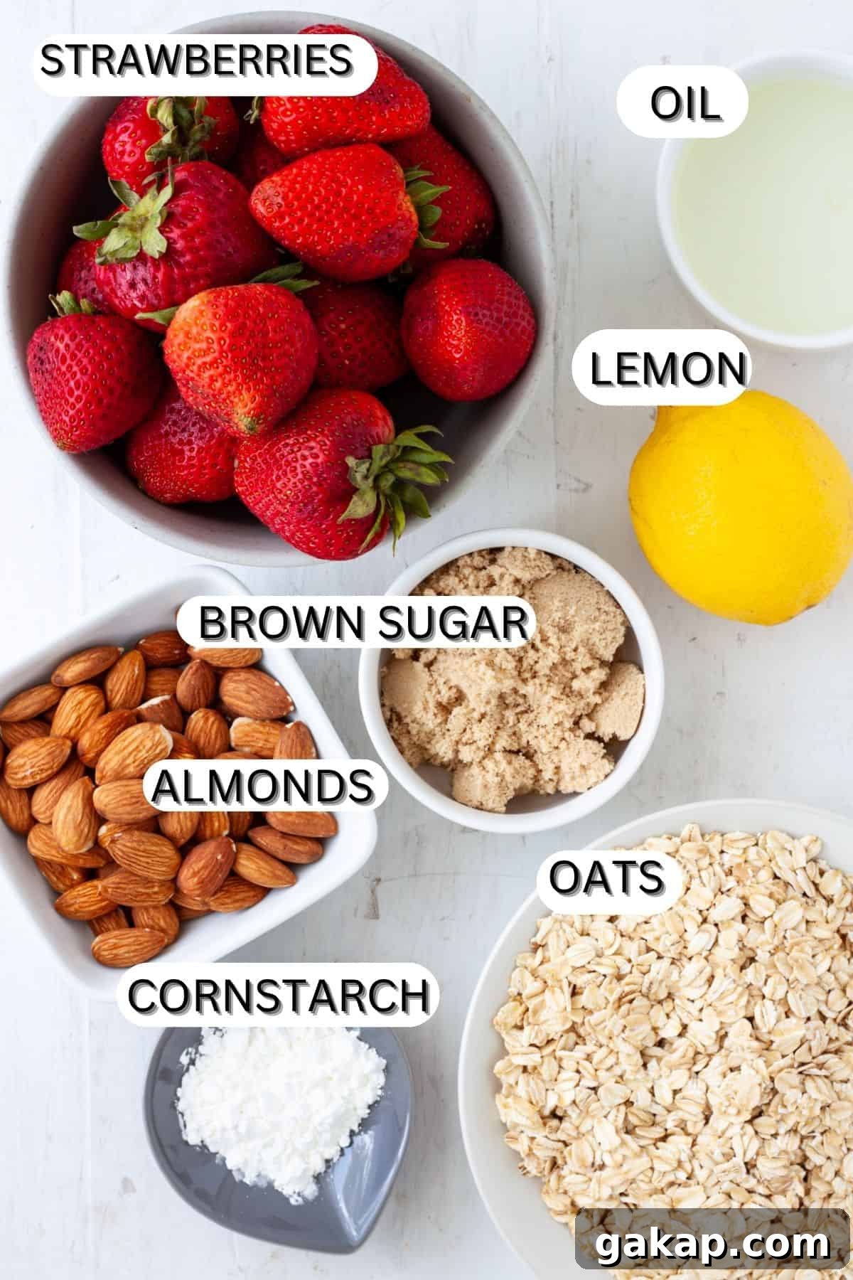 Ingredients for a strawberry crumble on a table and in small bowls.