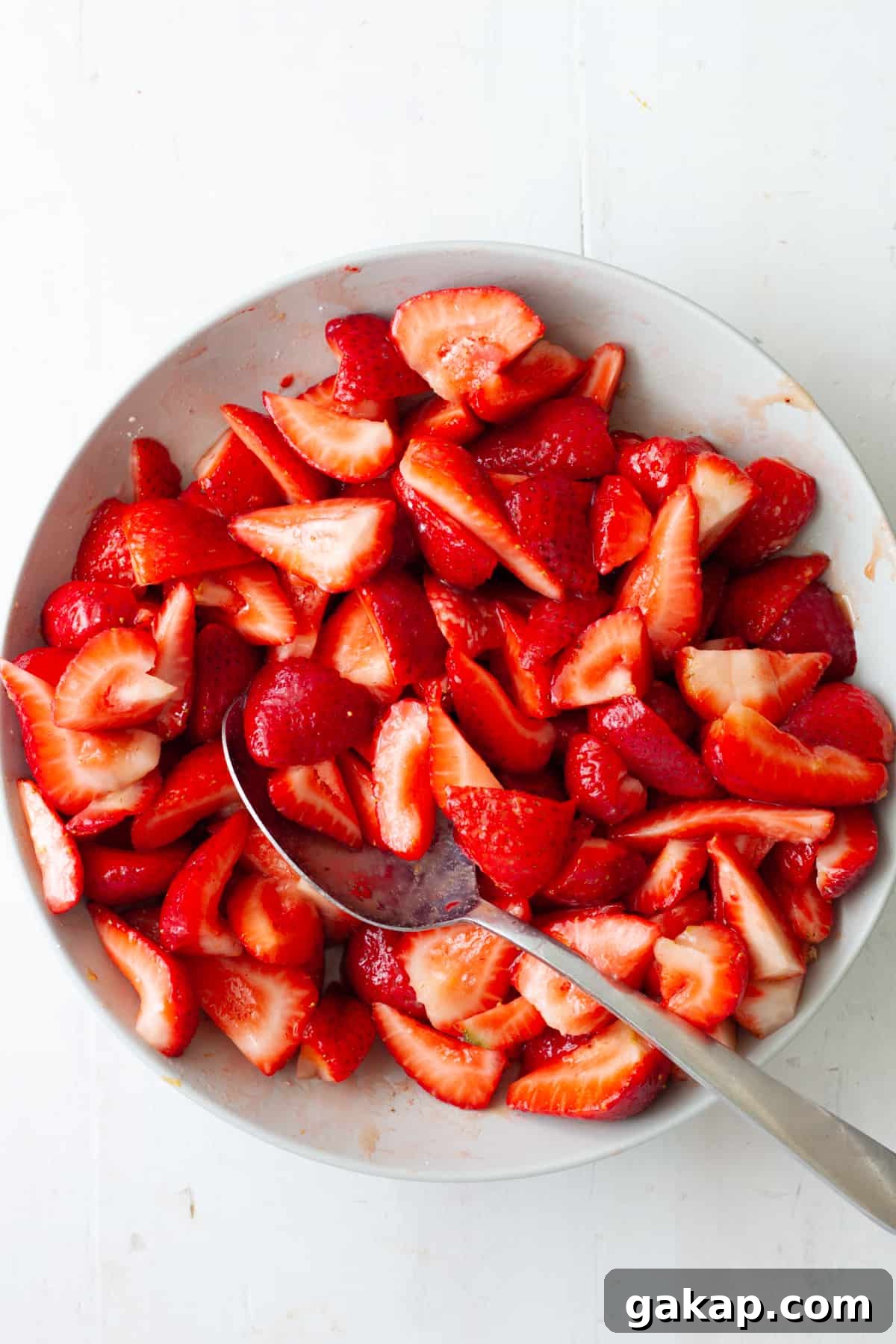 Strawberries mixed with sugar in a medium mixing bowl.