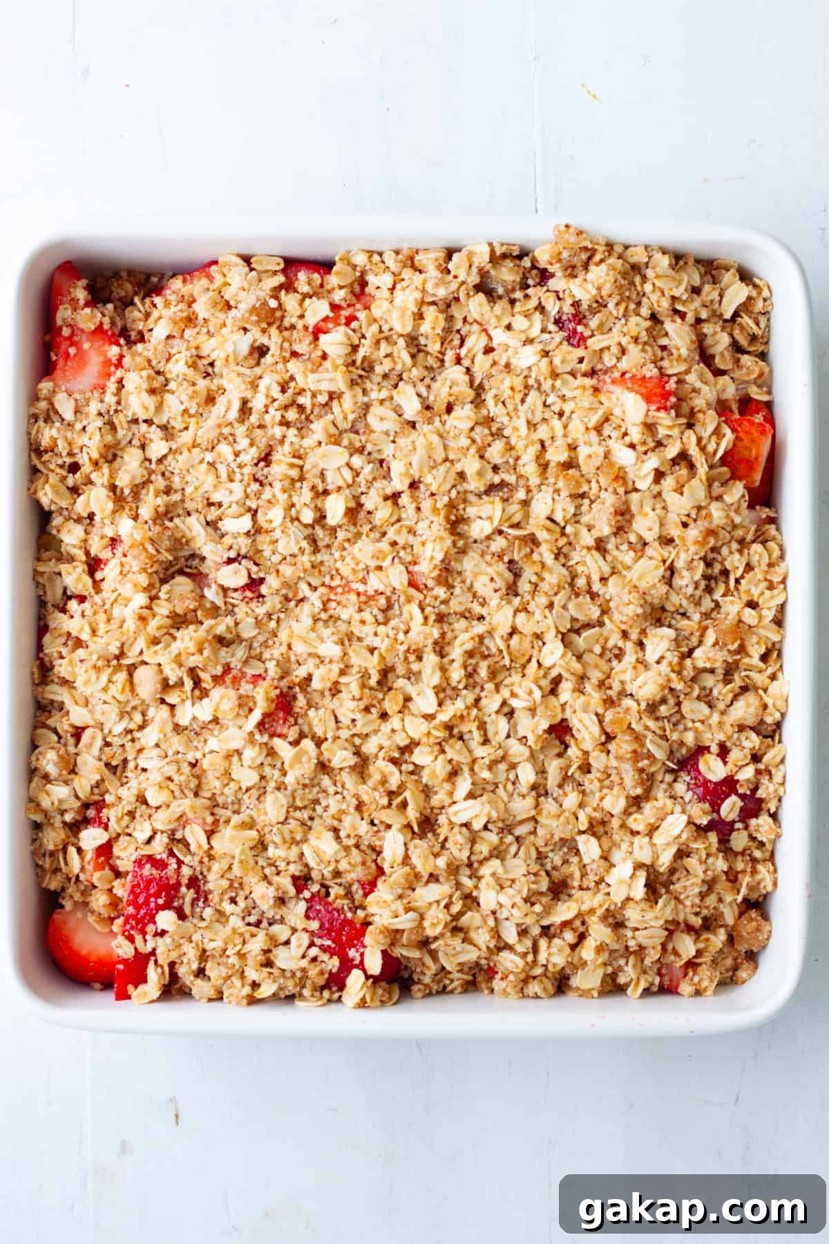 Strawberry crumble in a white baking dish topped with streusel.