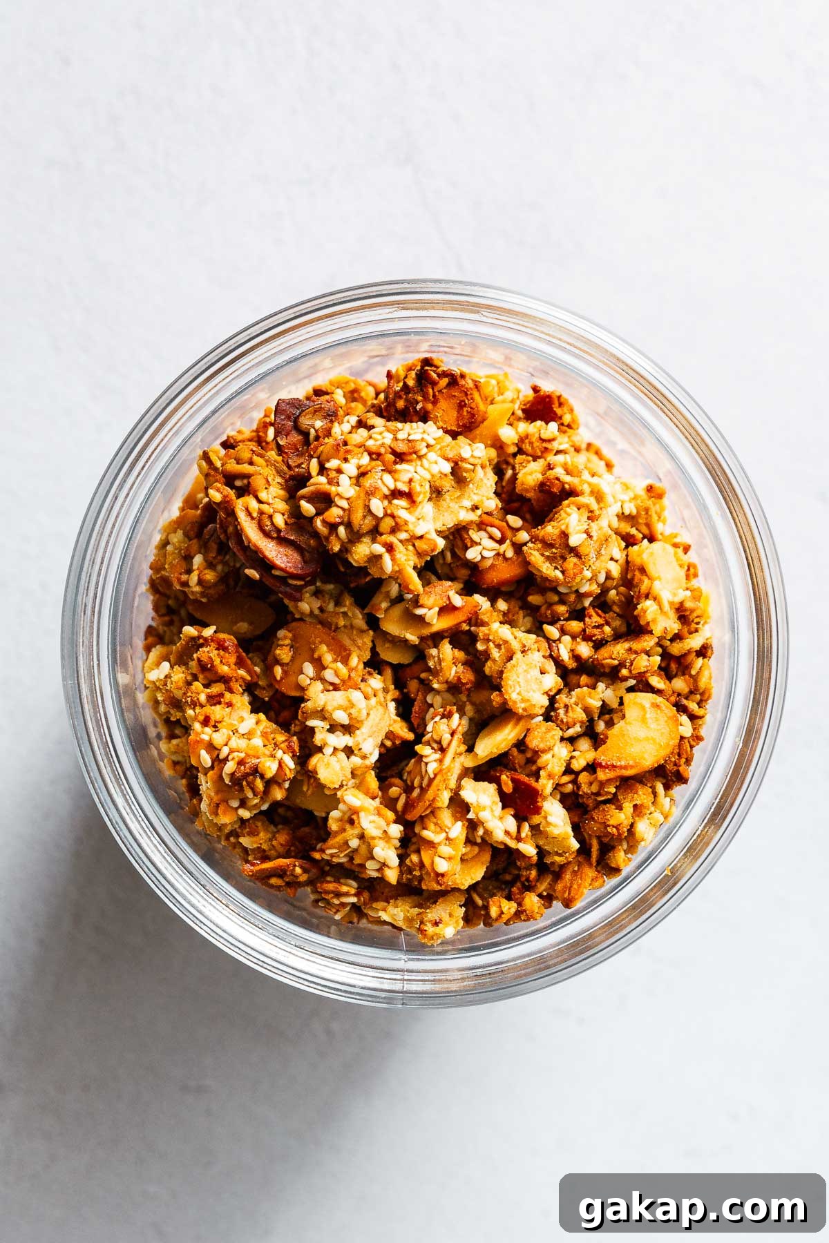 Tahini Sesame Granola with Honey and Orange Zest 8 Chunky tahini orange granola with sesame seeds and flaked almonds in glass jar.