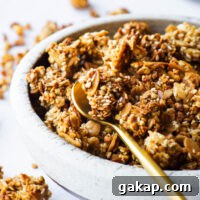 Tahini Sesame Granola with Honey and Orange Zest 10 A close-up of a bowl of sesame tahini with granola served with a gold spoon.