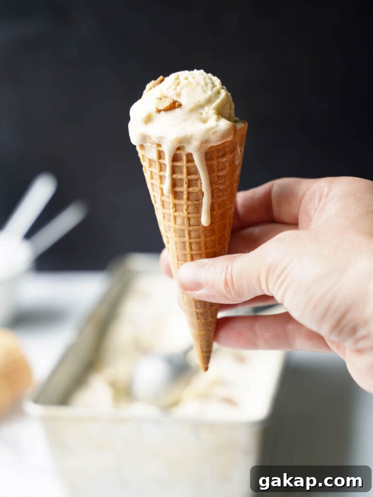 A hand holding an ice cream cone with peach ice cream