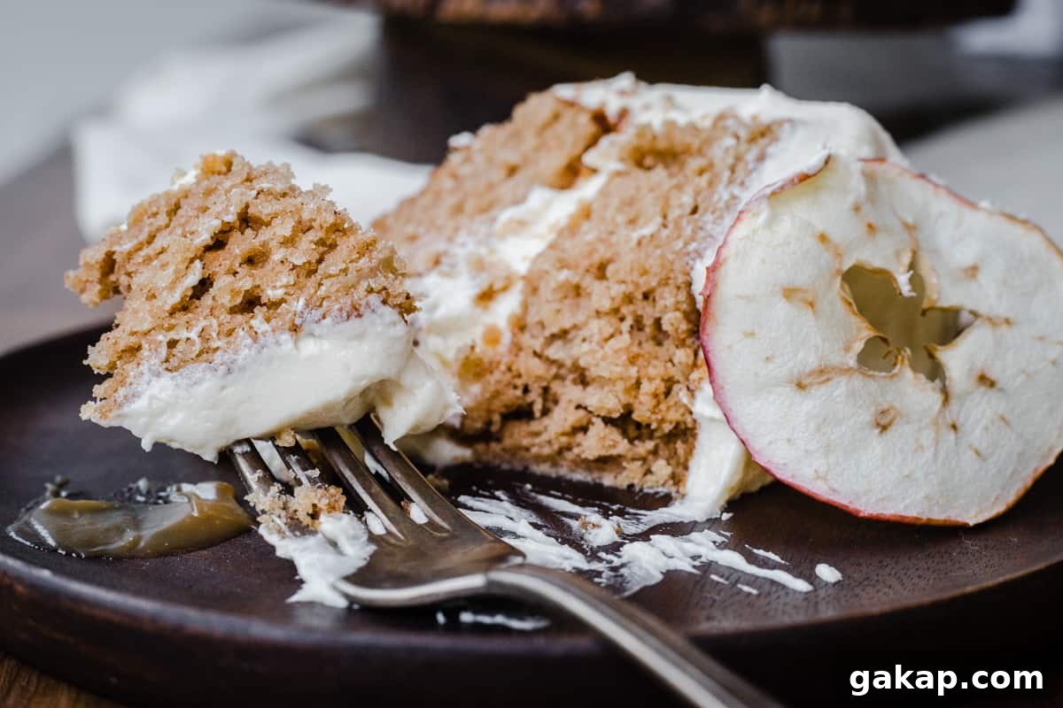 A forkful of taken out of a slice of Cinnamon Apple Cake with Salted Caramel Cream Cheese Buttercream on a wooden plate