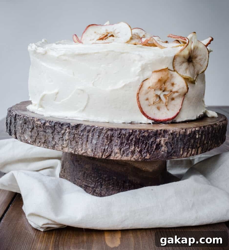 Apple and Cinnamon Cake with Salted Caramel Cream Cheese Buttercream on a cake stand on a wooden table.
