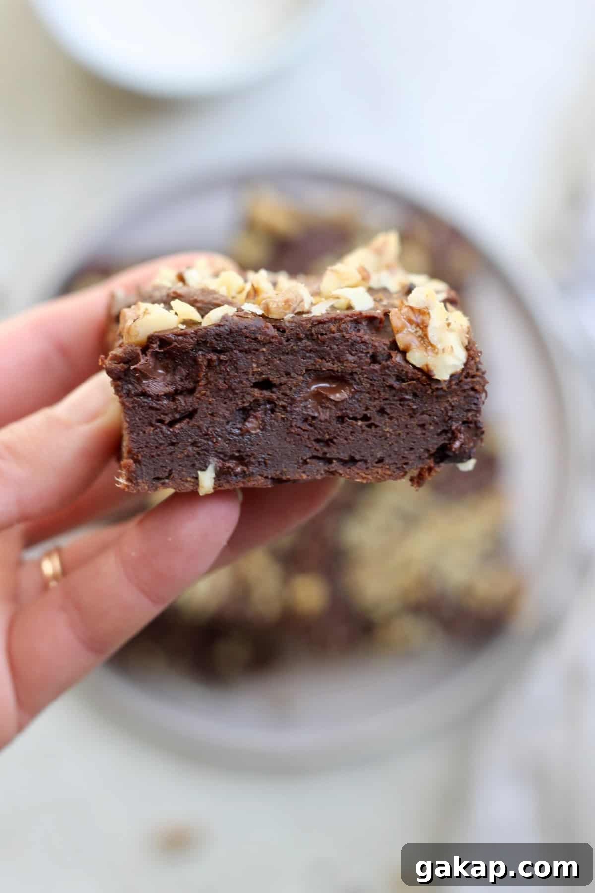 hand holding one brownie with walnuts.