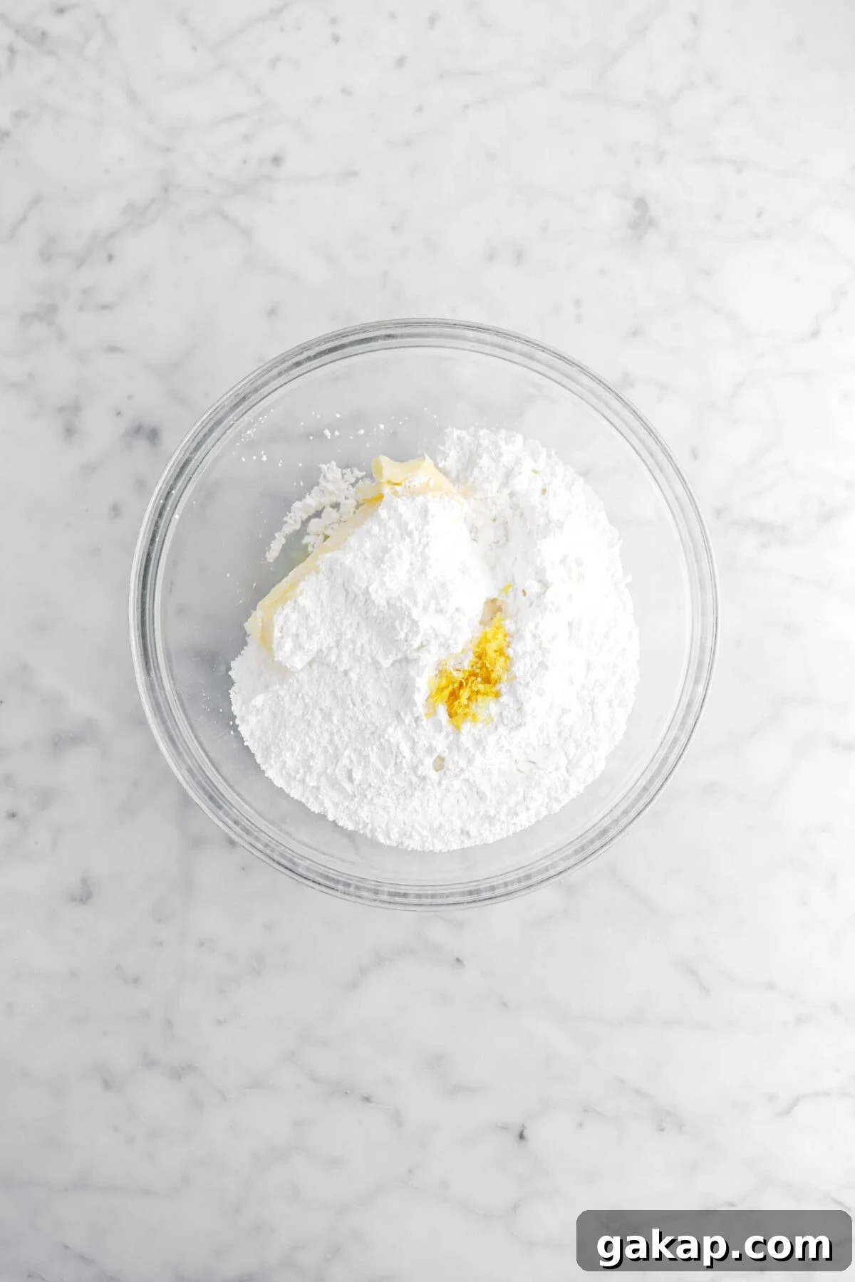 Lemon Blueberry Layer Cake with Zesty Lemon Buttercream 12 butter, powdered sugar, lemon juice, and lemon zest in glass bowl.