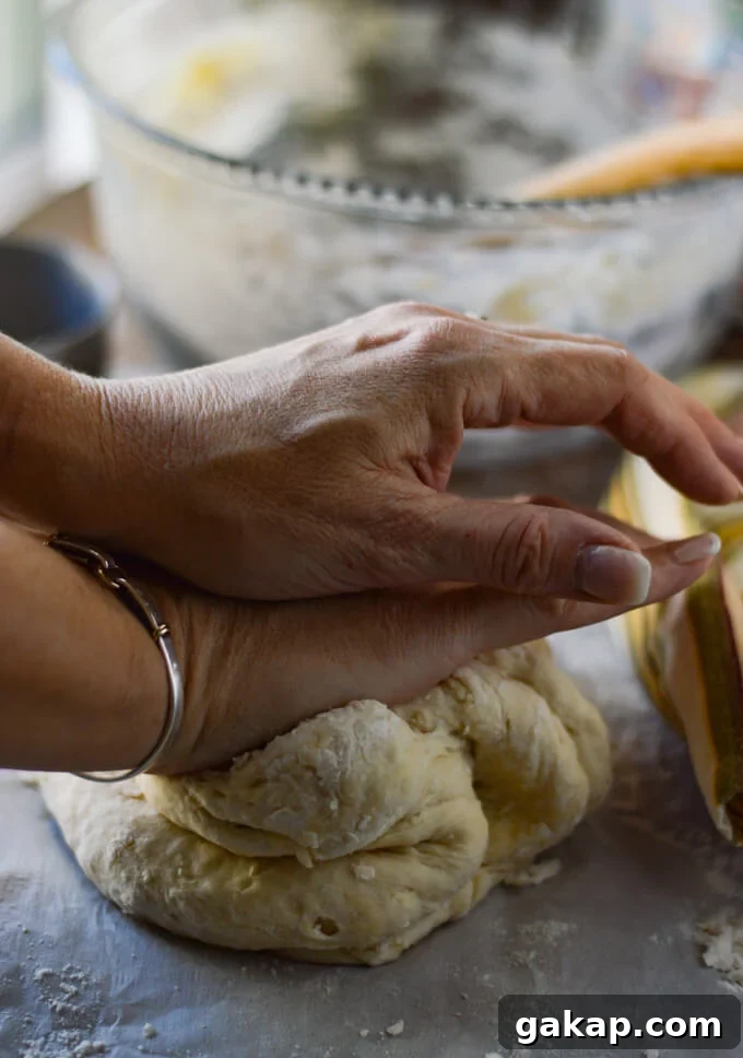 Crispy-Chewy Homemade Pizza Dough Recipe for Perfect Crust 5 Hands are kneading the pizza dough with a glass bowl in the back and a striped napkin beside the dough.