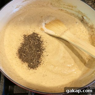 Black Pepper Paneer (Paneer Kali Mirch) — Spicy Indian Cottage Cheese 16 ground black pepper being added to a white color sauce in a pan