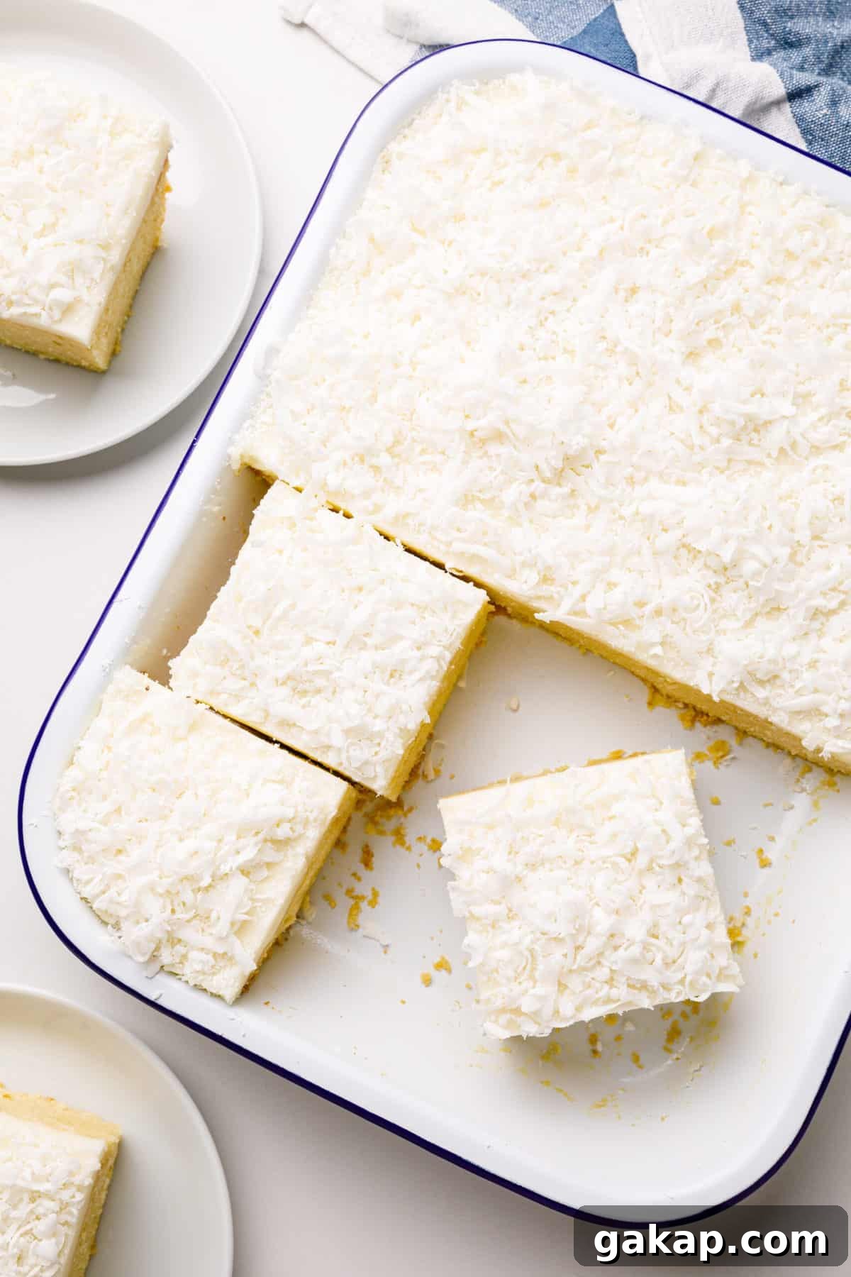 Classic Coconut Cake Recipe for Moist, Creamy Layers 8 coconut cake cut into square servings with coconut cream frosting in a 9x13 inch baking pan