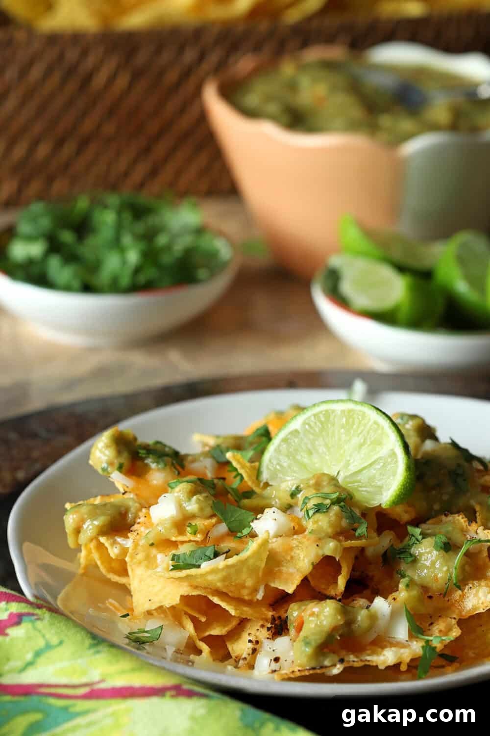 Tomatillo Salsa Verde used for Nachos, served on a white platter with lime and cilantro in bowls in background.