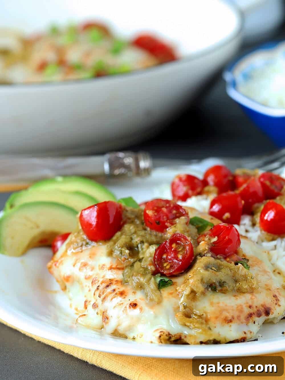 Tomatillo Salsa Verde is shown garnishing baked chicken with roasted cherry tomatoes.