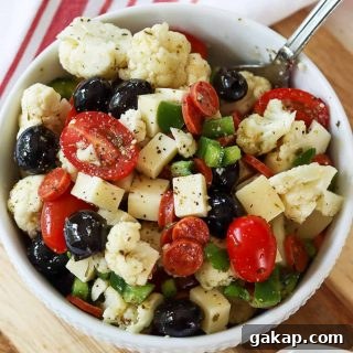 Square feature top down image of keto italian salad served in a white bowl with a spoon