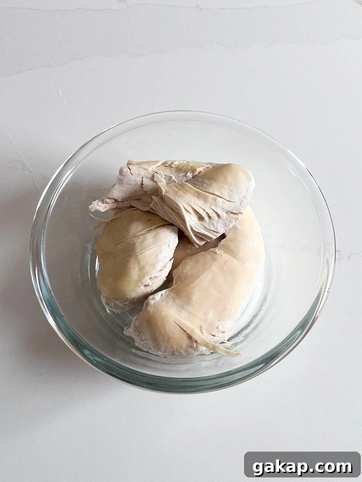 Cooked chicken breasts in a glass bowl.