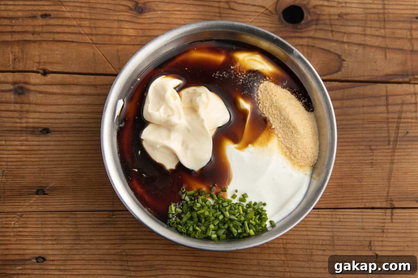 This is a picture of a bowl with greek yogurt, mayo, seasoning, and chives.