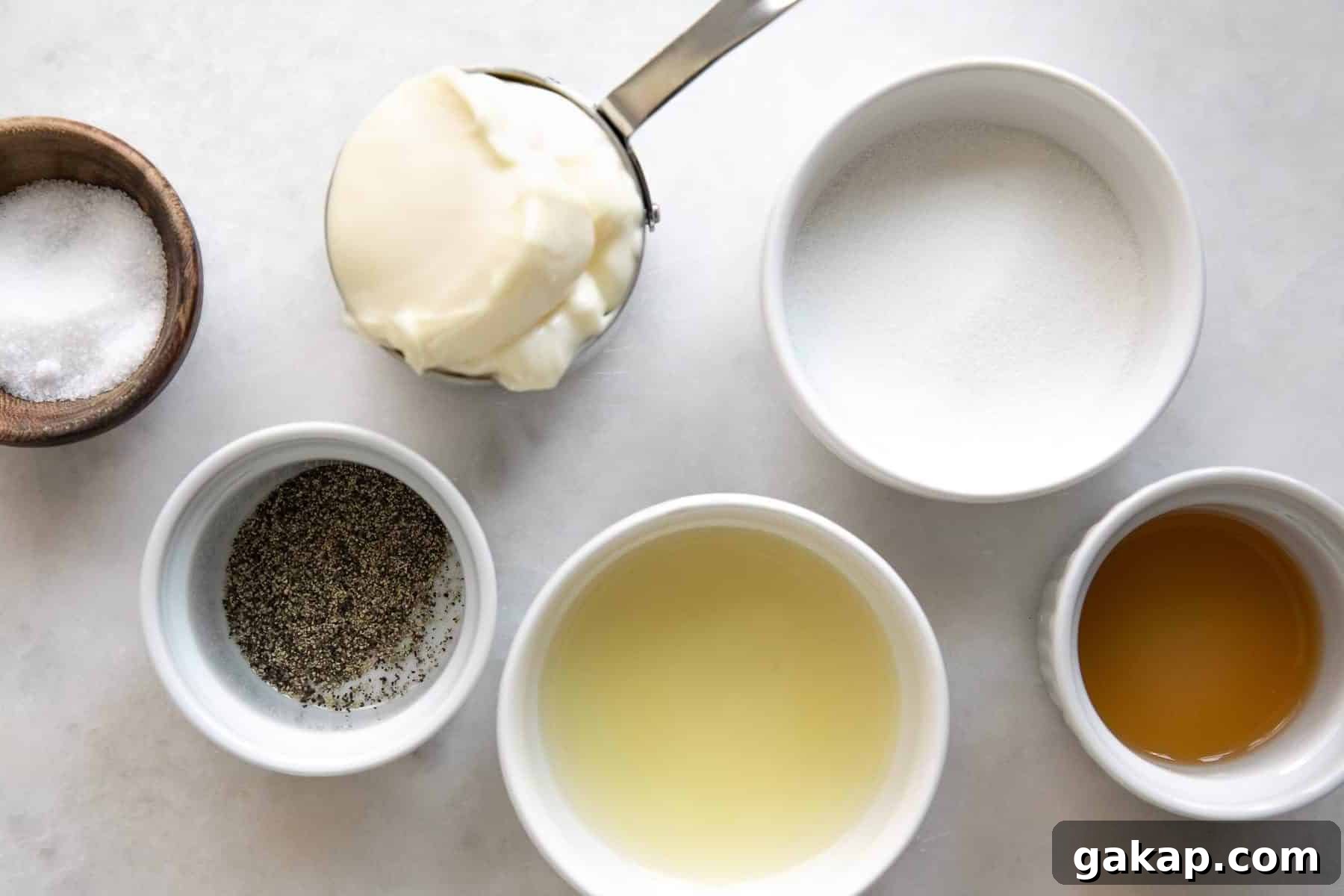 Coleslaw ingredients - pepper, mayonnaise, lemon juice, apple cider vinegar, and sugar.