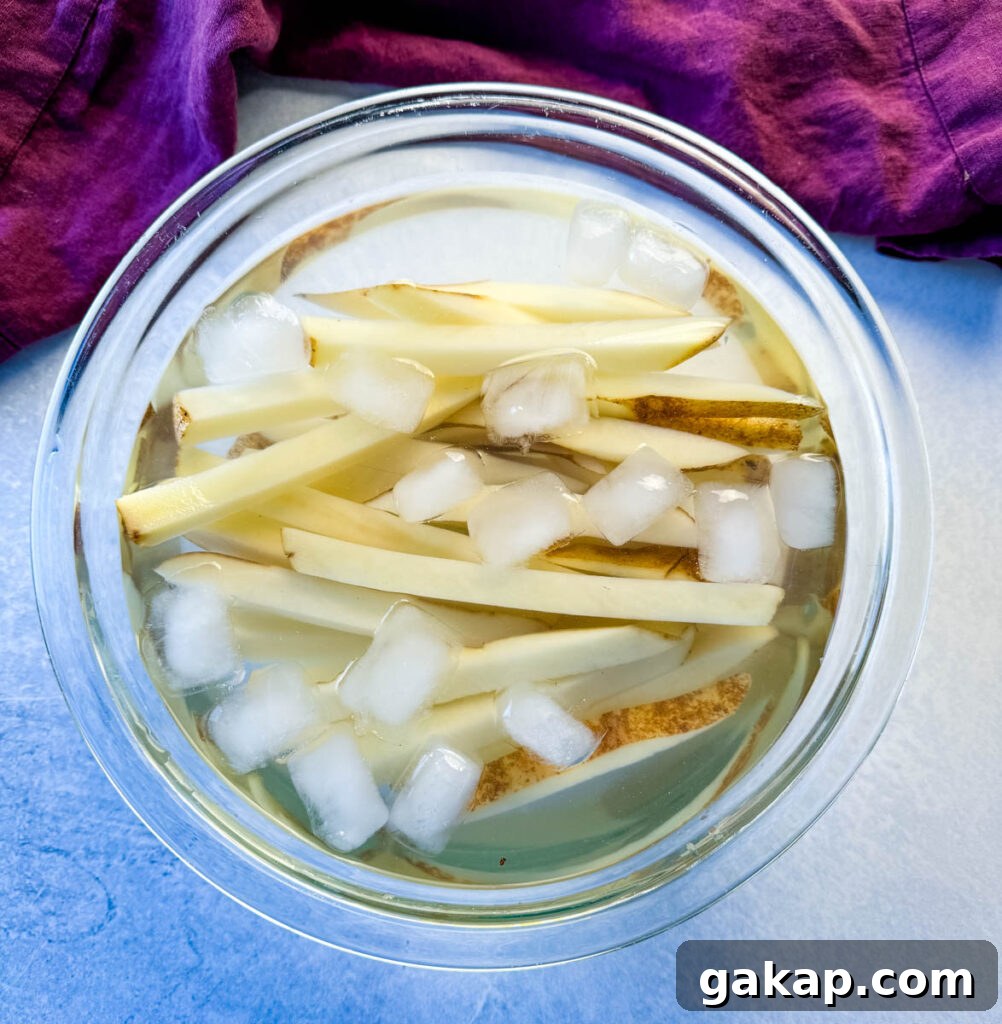 sliced potatoes with water and ice in a glass bowl