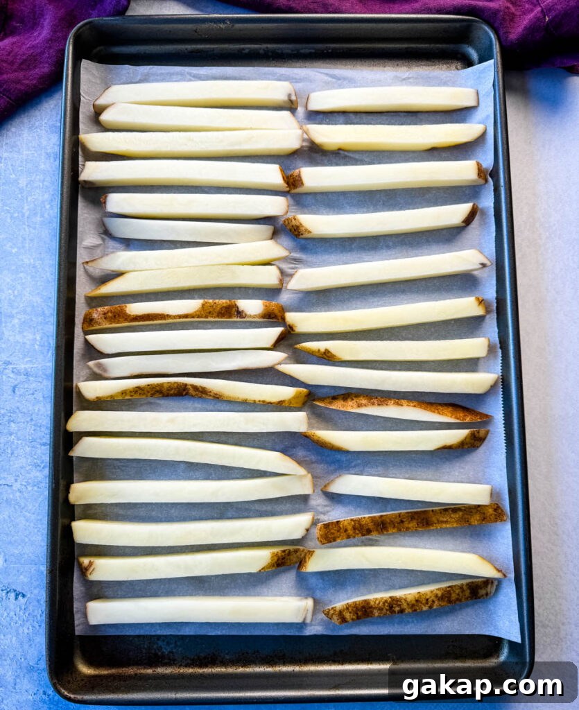 sliced potatoes on a sheet pan with parchment paper