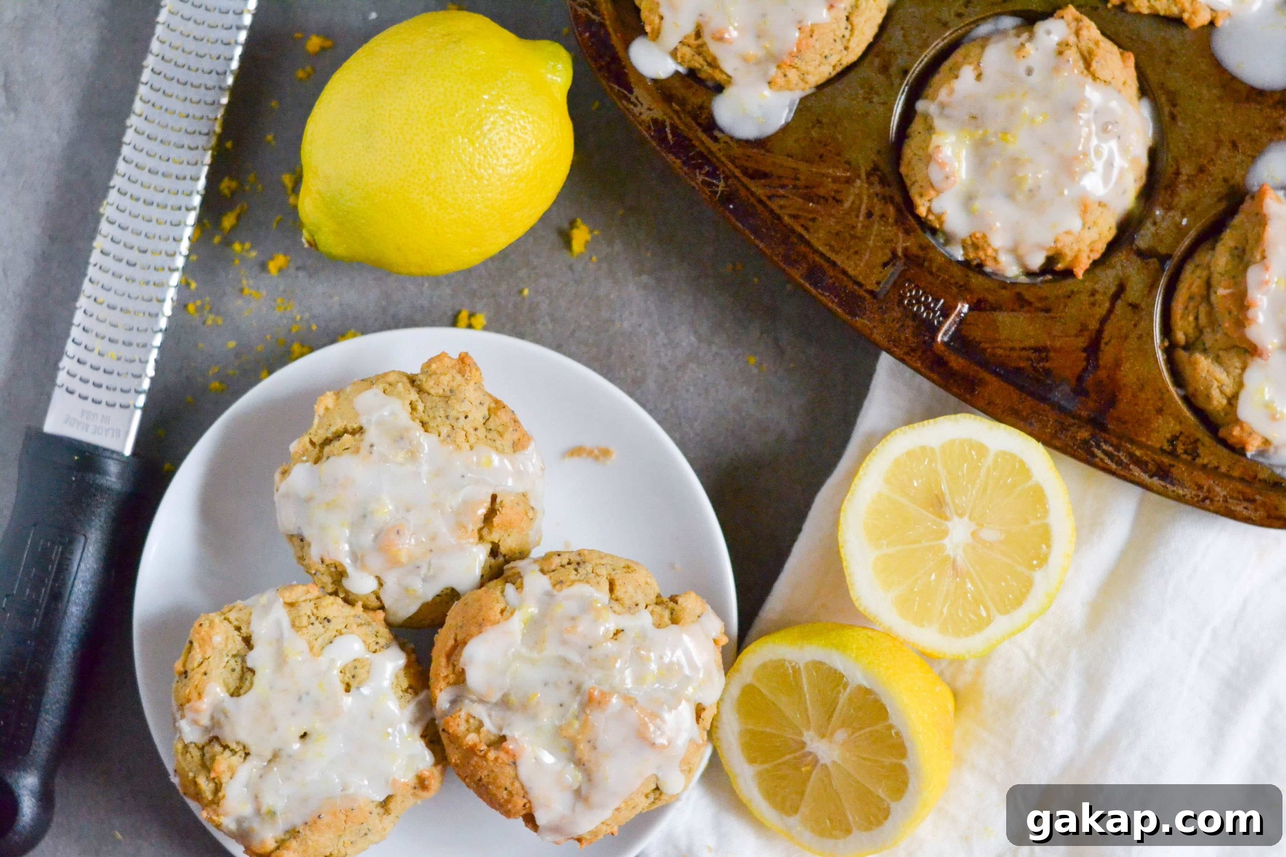 Gluten-Free Vegan Lemon Poppy Seed Muffins Recipe 3 A muffin pan with lemon poppyseed muffins in it with a plate next to it with three poppyseed muffins on it.