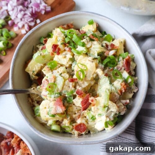 bowl with potato salad topped with spring onions and bacon