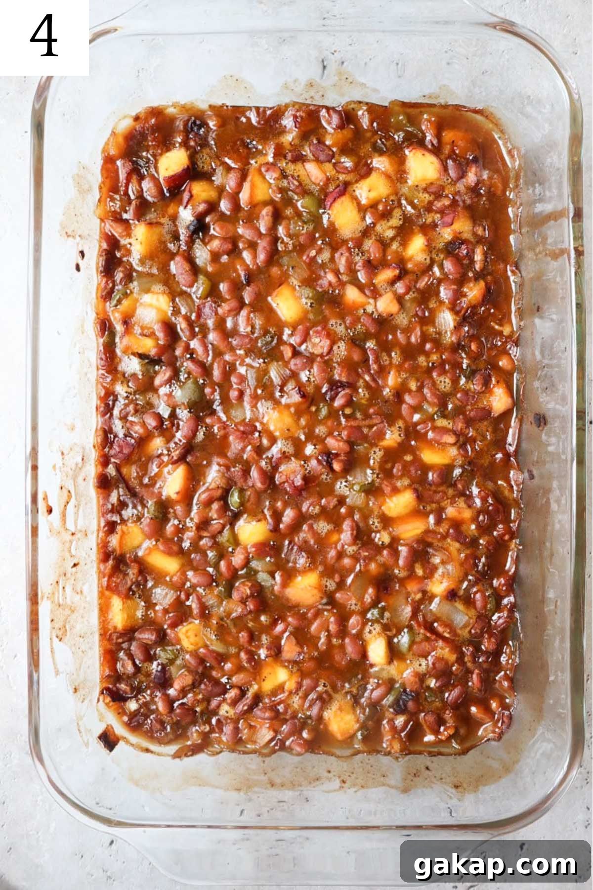Chipotle Peach Baked Beans Recipe for Sweet-Spicy BBQ Sides 7 glass baking dish with fully cooked peach baked beans.